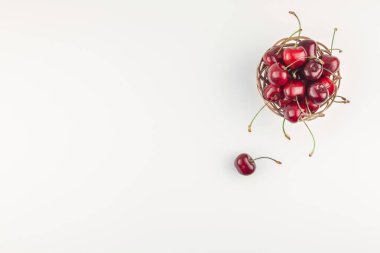 Yaratıcı üstten görünüm taze olgun kiraz kopya alanı ile küçük bir sepet içinde beyaz arka plan en az stili izole. Yaz eğlenceli ve sağlıklı beslenme kavramı. Metin veya gıda tasarımınız için şablon
