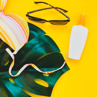 Tropikal orman palm monstera bırakır, güneş gözlüğü, Güneş kremi boş şişe mockup ve kadının mayo üstüne parlak kare Kağıt arka plan sarı. Yaz tatil yaratıcı düz yatıyordu kavramı şablonu