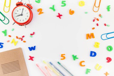 Çalar saat, renk okulu ve ofis malzemelerini kopya alanı, çerçeve, metin veya tasarım şablonu olan beyaz masa arkaplanına yerleştirerek okul kavramına yaslan
