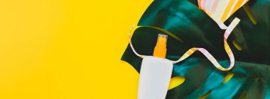 Tropikal orman palm monstera, güneş koruyucu boş şişe mockup ve kadının mayo parlak sarı Kağıt arka plan üzerinde bırakır. Yaz yaratıcı düz yatıyordu kavramı Şablon metnini tatiller. Uzun geniş afiş