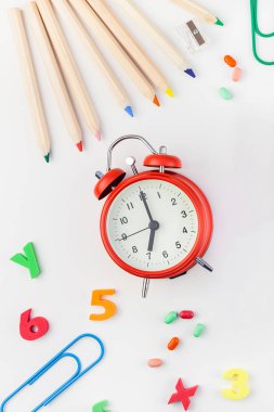 Çalar saat, renk okulu ve ofis malzemelerini kopya alanı, çerçeve, metin veya tasarım şablonu olan beyaz masa arkaplanına yerleştirerek okul kavramına yaslan