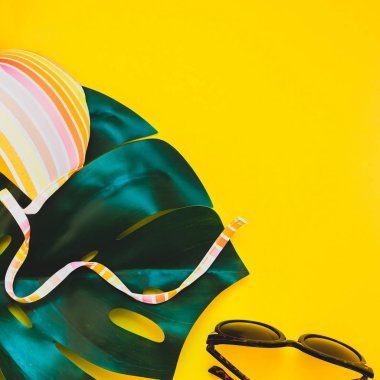 Tropikal orman palm monstera bırakır, güneş gözlüğü ve bir kadının mayo üstüne parlak kare Kağıt arka plan sarı. Metin için yaratıcı düz yatıyordu kavramı şablon yaz tatil