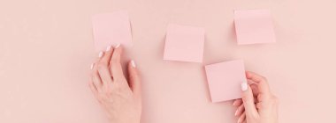 Bin yıllık pembe etiket kağıt ile çalışma masası uzun geniş afiş tutarak ve onları kopya alan arka plan en az tarzı ile duvara yapıştırma kadın elinde sahte posta o. Metin için şablon