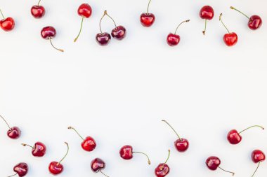 Minimal tarzda beyaz arka plan üzerinde izole kopya alanı ile taze olgun kiraz desen düzeninin yaratıcı üstten görünüm. Yaz eğlenceli ve sağlıklı beslenme kavramı. Metin veya gıda tasarımınız için şablon
