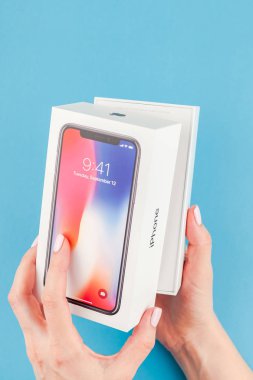 Berlin, Almanya - 24 Mayıs 2018: parlak mavi arka planı renkli kutuyu son Apple iphone X 10 akıllı telefon holding kadın eller. Unboxing kavramı kopya alanı ile