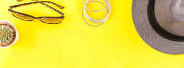 Düz gri şapka, kaktüs, bilezik ve güneş gözlüğü kalın sarı Kağıt arka plan üzerinde kopya alanı ile yatıyordu. Kadın rahat kıyafet havai görünümü. Uzun geniş afiş