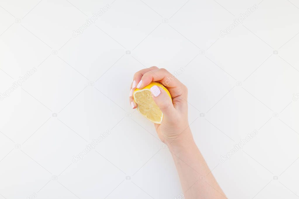 Woman hand with pastel manicure polish holding a half of lemon isolated on white background copy space minimalism style. Template for feminine social media. Healthy eating concept