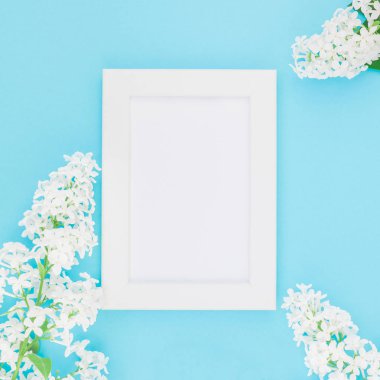 Boş Kartpostal çerçeve sahte kavramı en iyi görünümünü kare düz yığmak ve yaprakları kopya alanı en az stili, yazı, metin veya tasarım şablonu pastel mavi zemin üzerine beyaz leylak çiçekler