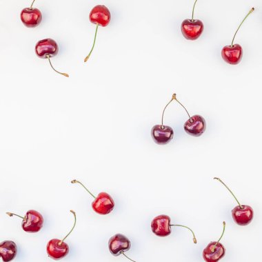 Üstten görünüm taze olgun kiraz desen düzeninin en az tarzında beyaz arka plan üzerinde izole kopya alanı ile kare. Yaz eğlenceli ve sağlıklı beslenme kavramı. Metin veya gıda tasarımınız için şablon