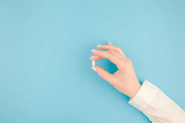 Frau Hält Eine Weiße Pille Auf Pastellblauem Papierhintergrund Mit Kopierraum — Stockfoto