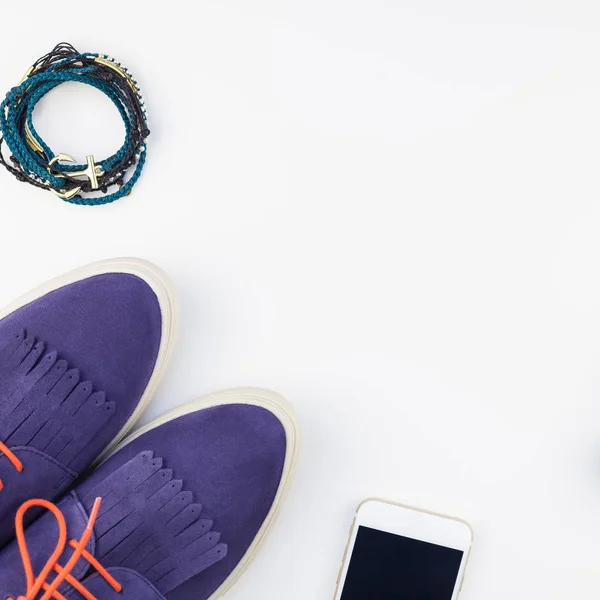 方形平躺的麂皮绒鞋 蓝色牛仔裤 手镯和智能手机与耳机在白色背景与复制空间 女性休闲服装的头顶景色 时髦的时髦的看顶部视图 — 图库照片