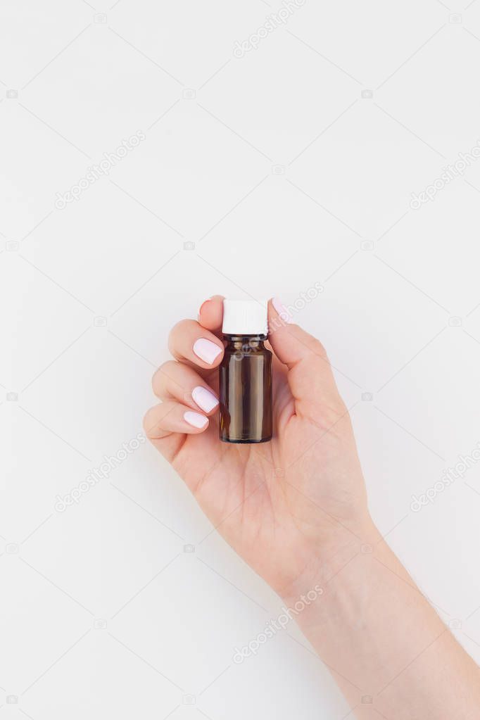 Woman hand with pastel manicure polish holding small glass bottle isolated white background with copy space. Mock up for natural oil spa treatment, medical products. Female healthcare wellness concept