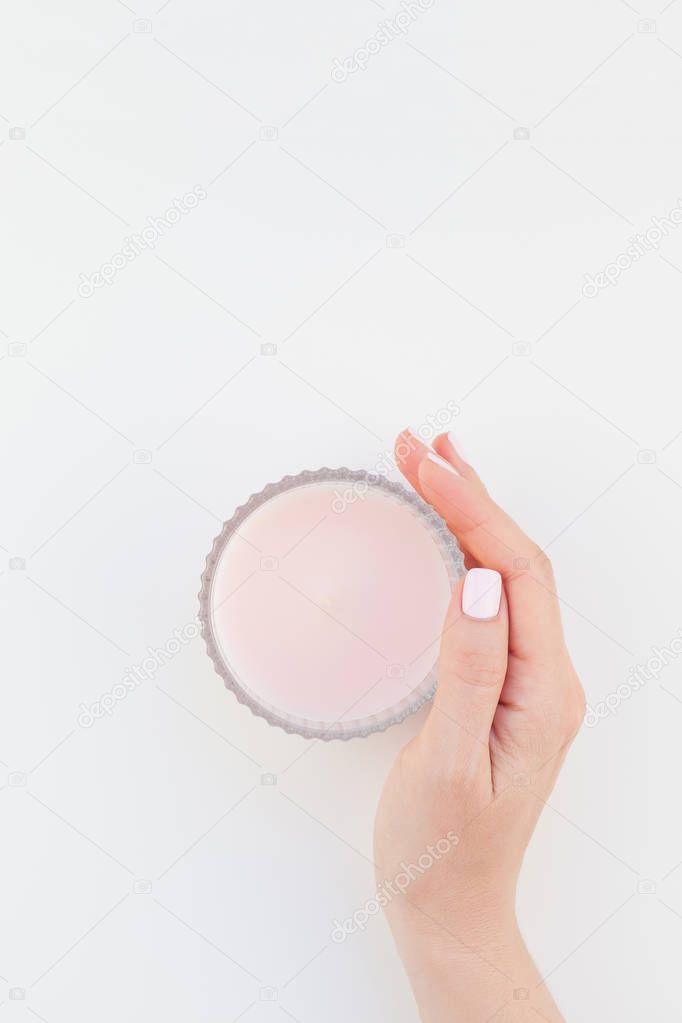 Woman hand with pastel manicure polish holding pink aromatic candle isolated on white background with copy space. Template for feminine beauty blog social media. Spa and wellness concept