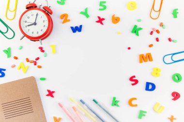 Çalar saat, renk okulu ve ofis malzemelerini kopya alanı, çerçeve, metin veya tasarım şablonu olan beyaz masa arkaplanına yerleştirerek okul kavramına yaslan