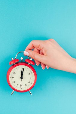 Yaratıcı düz yatıyordu kavramı kırmızı vintage çalar saat parlak mavi turkuaz üzerinde tutan kadın el üst görünümünü renk Kağıt arka plan kopya alanı ile en az tarzı, metin için şablon