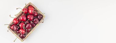 Kopya alanı ile küçük bir sepet içinde taze olgun kiraz uzun geniş afiş beyaz arka plan en az stili izole. Yaz eğlenceli ve sağlıklı beslenme kavramı. Metin veya gıda tasarımınız için şablon