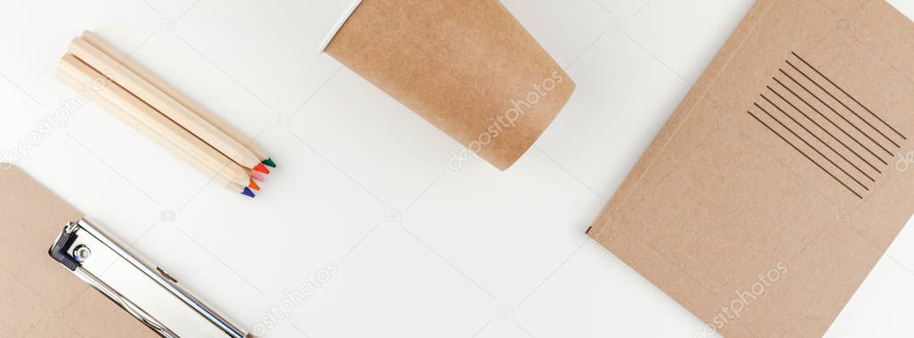 Long wide banner flat lay of workspace desk styled recycled brown design office supplies and coffee cups with copy space white table background minimal eco style. Concept of environmental protection