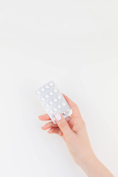 Woman hand with pastel manicure polish holding pills in blister isolated on white background with copy space. Template for feminine beauty blog social media. Female healthcare concept