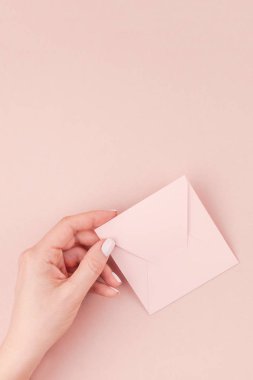 Kadın el kopya alanı bin yıllık pembe bir arka plan üzerinde küçük aşk mektubu minimalizm tarzı tutarak yaratıcı görüntü. Kavram şablon kadınsı blog, sosyal medya için