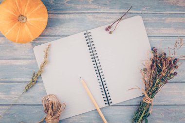 Üstten görünüm sonbahar turuncu kabak ve kuru çiçek çimen şükran günü arka plan üzerinde mavi ile defter sahte ile ahşap masa tonda ve rustik tarzı, metin için şablon alanı Kopyala