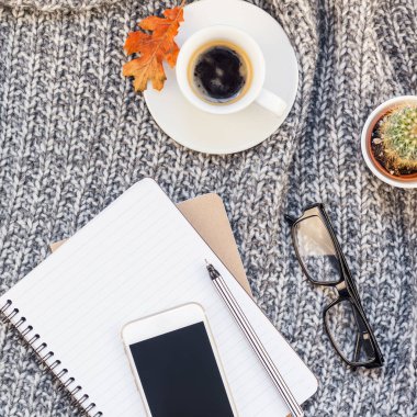Yaratıcı bir şekilde sonbahar düz ek yükü üstten görünüm şık ev çalışma alanı smartphone defter kahve fincanı sıcak gri örgü ekose arka plan kopya alanı yatıyordu. Sonbahar sezonu şablon kadınsı blog sosyal medya