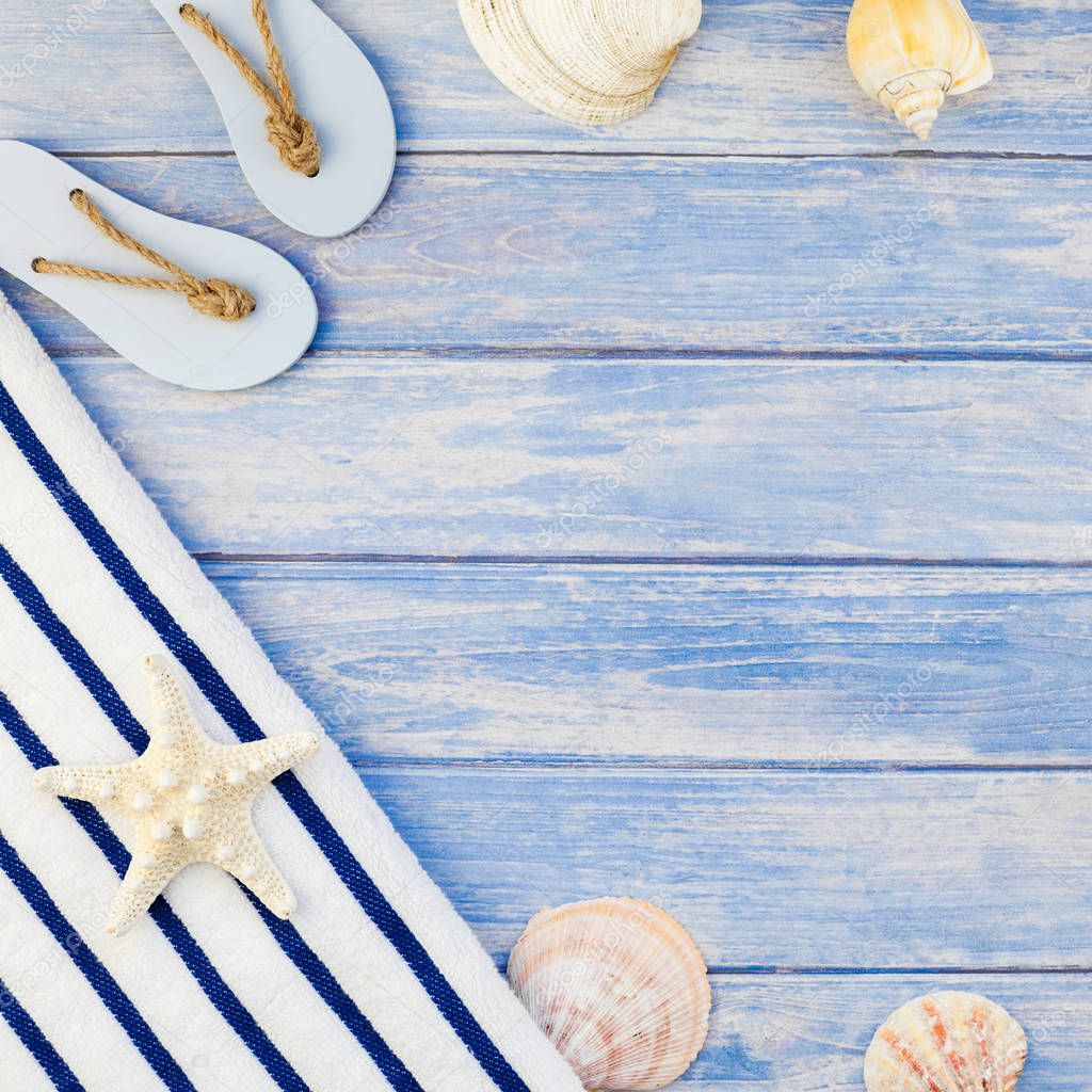 Creative flat lay concept summer travel vacations. Top view of towel flip flops seashells and starfish on pastel blue wooden planks background with copy space rustic style square frame template text