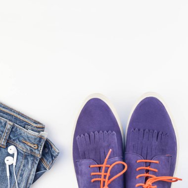 Kare düz süet ayakkabı, kot ve akıllı telefon kulaklık kopya alanı beyaz zemin üzerine yatırın. Kadın rahat kıyafet havai görünümü. Trendy hipster bak üstten görünüm