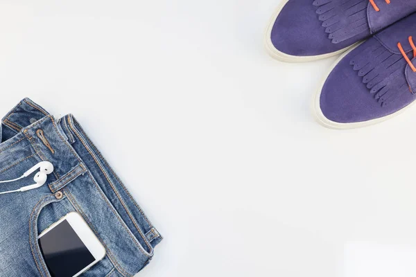 Platt Låg Mockaskor Blå Jeans Och Smartphone Med Hörlurar Vit — Stockfoto