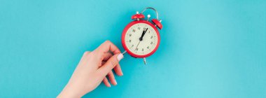 Yaratıcı düz yatıyordu kavramı kırmızı vintage çalar saat parlak mavi turkuaz üzerinde tutan kadın el üst görünümünü renk Kağıt arka plan kopya alanı ile minimal tarzda uzun geniş afiş