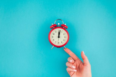 Yaratıcı düz yatıyordu kavramı kırmızı vintage çalar saat parlak mavi turkuaz üzerinde tutan kadın el üst görünümünü renk Kağıt arka plan kopya alanı ile en az tarzı, metin için şablon