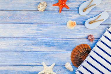 Yaratıcı düz yaz seyahat tatil kavramı yatıyordu. Deniz kabuklarını ve deniz yıldızı kopya alanı rustik tarzı çerçeve şablonu metin pastel mavi ahşap plakalar zemin üzerine üstten görünüm havlu Flip floplar