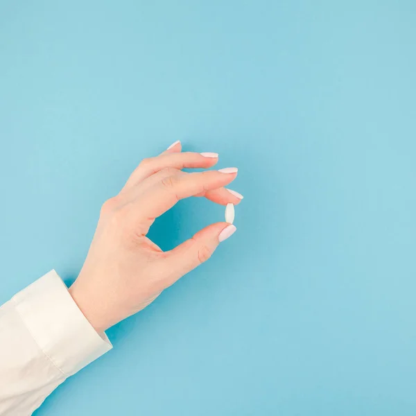 最小限のスタイル テキストの正方形テンプレートのコピー スペースとパステル調の青紙の背景に白い錠剤を持つ女性の手 医療の概念 — ストック写真