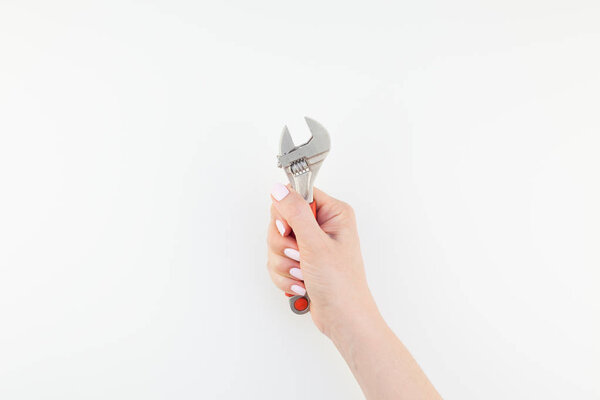 Creative image of woman hand with pastel manicure polish holding spanner with copy space isolated on white background in minimalism style. Repair or improvement feminism concept