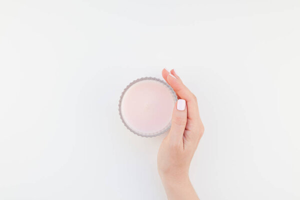 Woman hand with pastel manicure polish holding pink aromatic candle isolated on white background with copy space. Template for feminine beauty blog social media. Spa and wellness concept