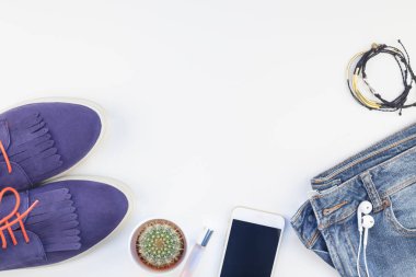 Düz beyaz arka plan kopya alanı ile kulaklıktan süet ayakkabı, kot, bilezik kaktüs ve akıllı telefon yatırın. Kadın rahat kıyafet havai görünümü. Trendy hipster bak üstten görünüm