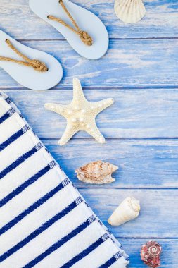 Yaratıcı düz yaz seyahat tatil kavramı yatıyordu. Deniz kabuklarını ve deniz yıldızı kopya alanı rustik tarzı çerçeve şablonu metin pastel mavi ahşap plakalar zemin üzerine üstten görünüm havlu Flip floplar