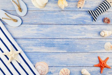 Yaratıcı düz yaz seyahat tatil kavramı yatıyordu. Deniz kabuklarını ve deniz yıldızı kopya alanı rustik tarzı çerçeve şablonu metin pastel mavi ahşap plakalar zemin üzerine üstten görünüm havlu Flip floplar