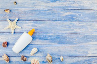 Yaratıcı düz kavramı yaz seyahat tatil yatıyordu. Pastel mavi ahşap plakalar arka plan kopya alanı rustik tarzı, çerçeve şablonu metin üzerinde güneş kremi şişe mockup kabukları ve denizyıldızı üstten görünüm
