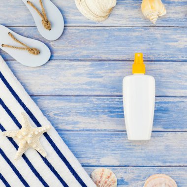 Yaratıcı düz yaz seyahat tatil kavramı yatıyordu. En iyi plaj havlu güneş kremi şişe flip flop deniz kabuklarını denizyıldızı pastel mavi ahşap plakalar arka plan kopya alanı mockup şablon metin görünümünü kare