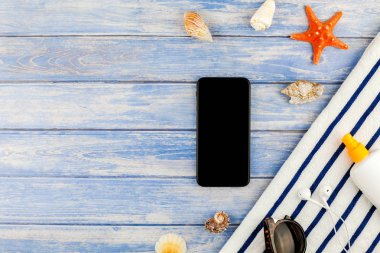 Yaratıcı düz yaz seyahat tatil kavramı yatıyordu. Plaj havlusu smartphone deniz kabuğu denizyıldızı üstten görünüm Kopyala yer mockup template metin için pastel mavi ahşap plakalar zemin üzerine