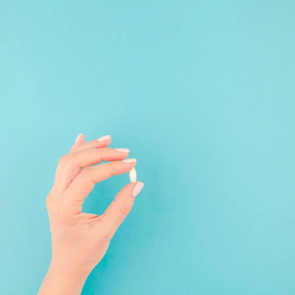 Frau Hält Eine Weiße Pille Auf Pastellblauem Papierhintergrund Mit Kopierraum — Stockfoto