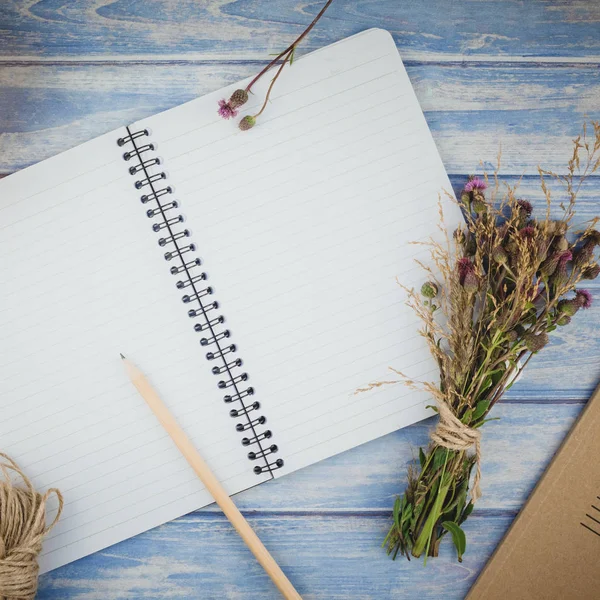 Square Top view of autumn dry flowers with grass background over blue toned wooden table with notebook mock up and copy space in rustic style, template for text