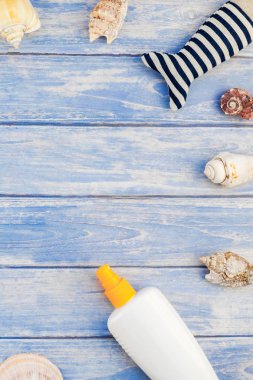 Yaratıcı düz yaz seyahat tatil kavramı yatıyordu. Deniz kabuğu denizyıldızı pastel mavi ahşap plakalar arka plan kopya alanı mockup şablon metin ile üstten görünüm plaj havlusu güneş kremi şişe Flip floplar