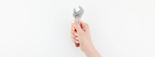 Creative wide long banner of woman hand with pastel manicure polish holding spanner with copy space isolated on white background in minimalism style. Repair or improvement feminism concept