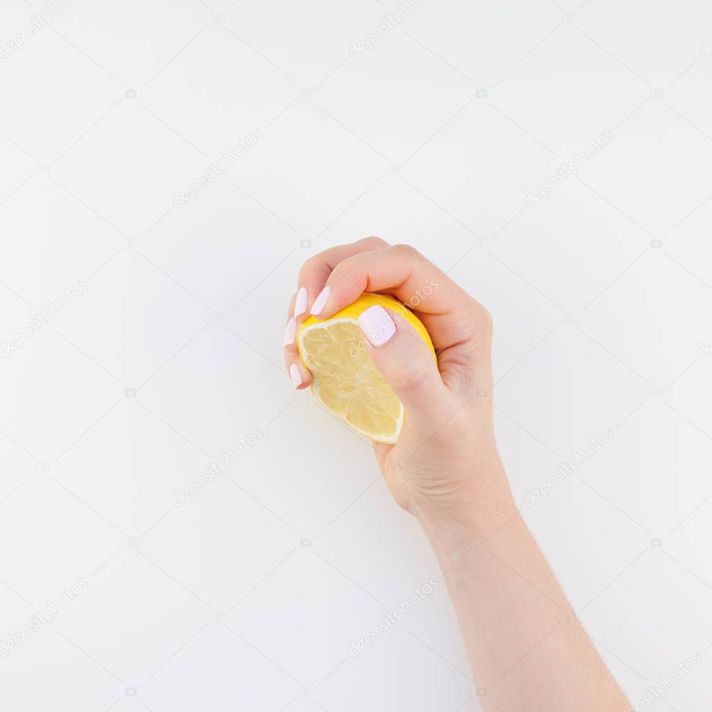 Woman hand with pastel manicure polish holding a half of lemon isolated on white background copy space minimalism style. Square Template for feminine social media. Healthy eating concept