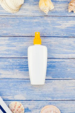 Yaratıcı düz yaz seyahat tatil kavramı yatıyordu. Deniz kabuğu denizyıldızı pastel mavi ahşap plakalar arka plan kopya alanı mockup şablon metin ile üstten görünüm plaj havlusu güneş kremi şişe Flip floplar