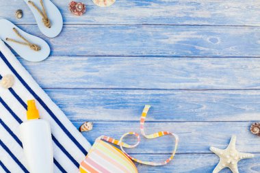 Yaratıcı düz yaz seyahat tatil kavramı yatıyordu. Plaj havlusu güneş kremi şişe mayo deniz kabuklarını denizyıldızı üstten görünüm kopya alanı mockup şablon metin pastel mavi ahşap plakalar zemin üzerine