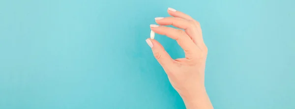 Mano Mujer Sosteniendo Una Píldora Blanca Sobre Fondo Papel Azul — Foto de Stock