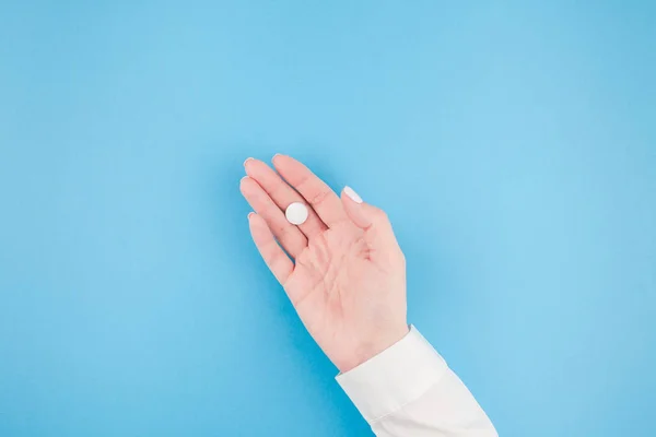 Mano Mujer Sosteniendo Una Píldora Blanca Sobre Fondo Papel Azul —  Fotos de Stock