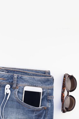 Düz beyaz arka plan kopya alanı ile kulaklıktan süet ayakkabı, kot, bilezik ve smartphone yatırın. Kadın rahat kıyafet havai görünümü. Trendy hipster bak üstten görünüm